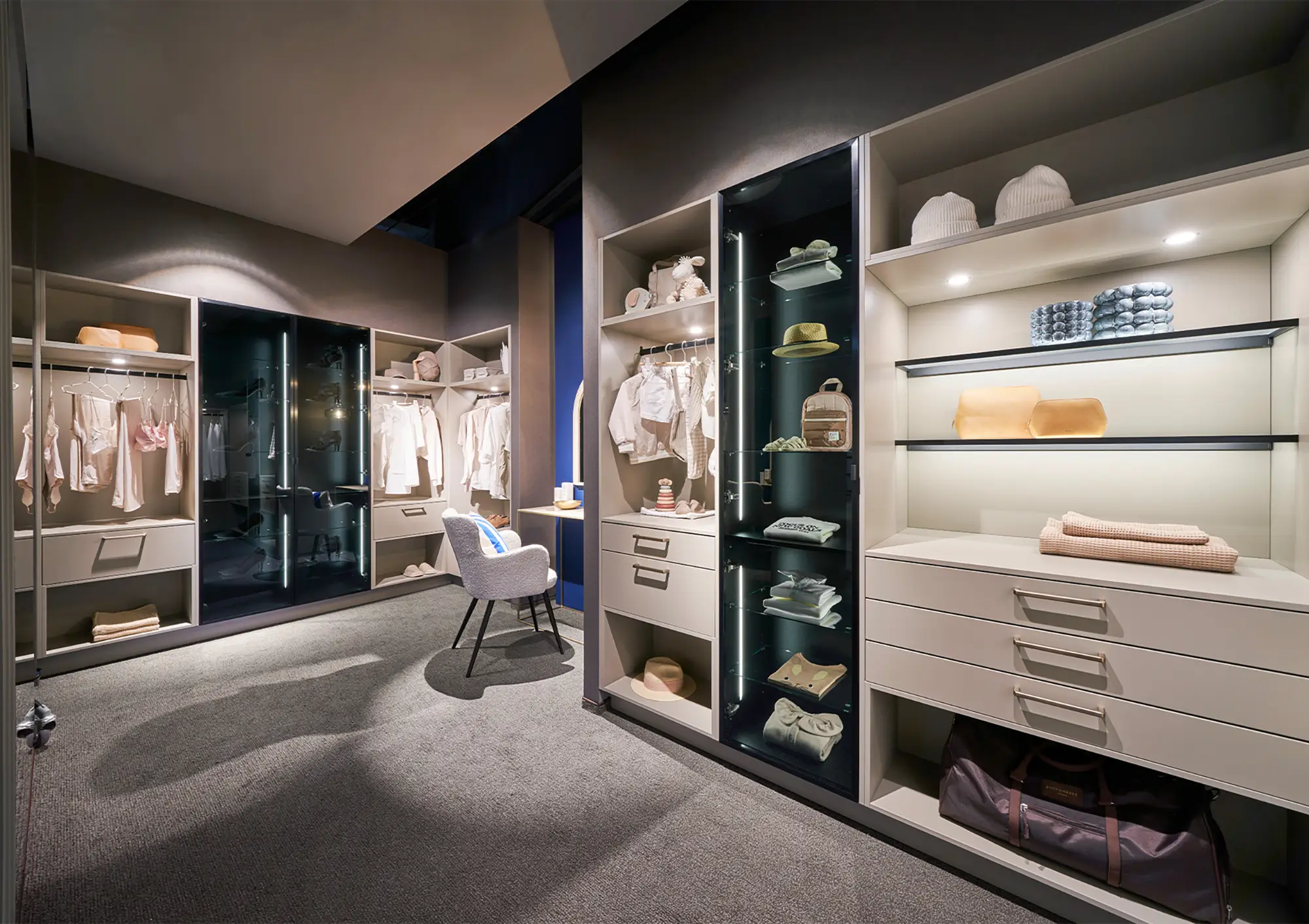 Grand dressing moderne avec penderies ouvertes, vitrines éclairées et rangements sur mesure.