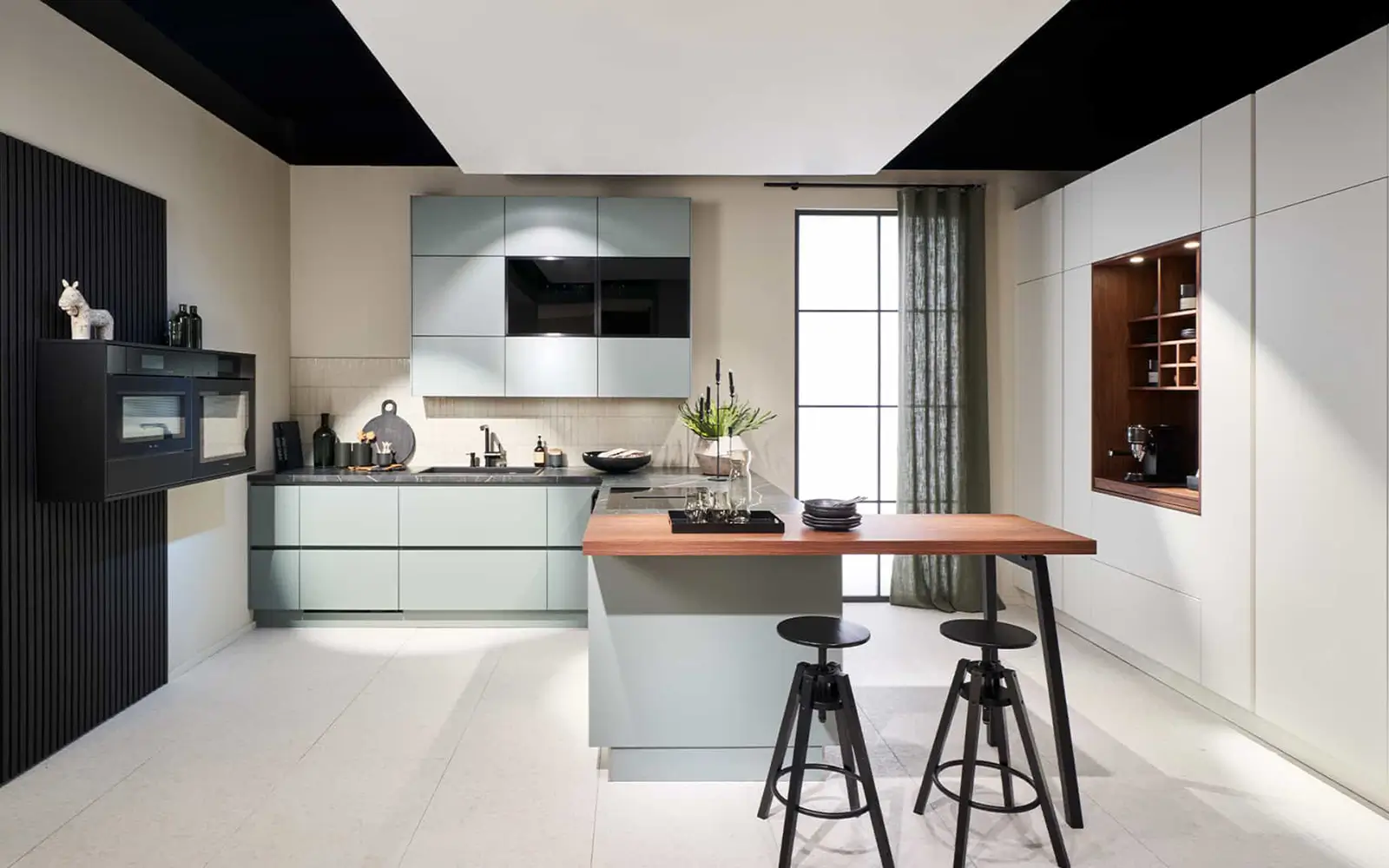 Cuisine moderne vert pastel avec îlot et comptoir en bois, rangements intégrés et coin café.